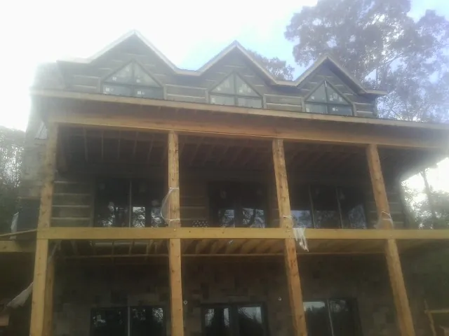Dormers and porch framing on a large log home under construction — Roof Coating work by our crew in Seymour